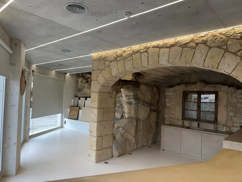 Arco de sillería con roca artificial e iluminación lineal en el showroom de 3Pols