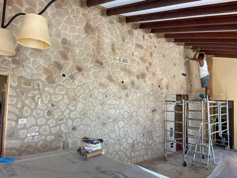 Artesano trabajando desde un andamio en una pared interior de piedra tematizada