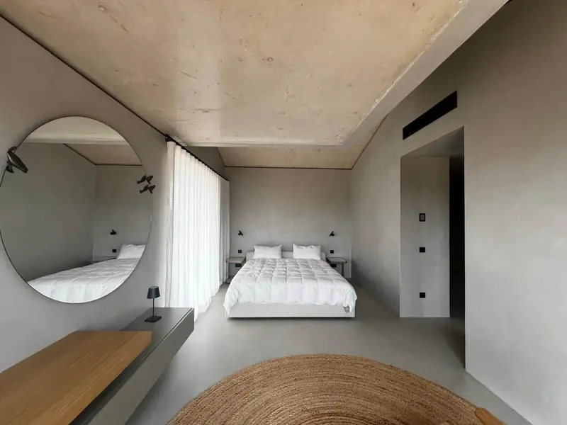 Dormitorio revestido por completo en microcemento gris: suelo, paredes y techo