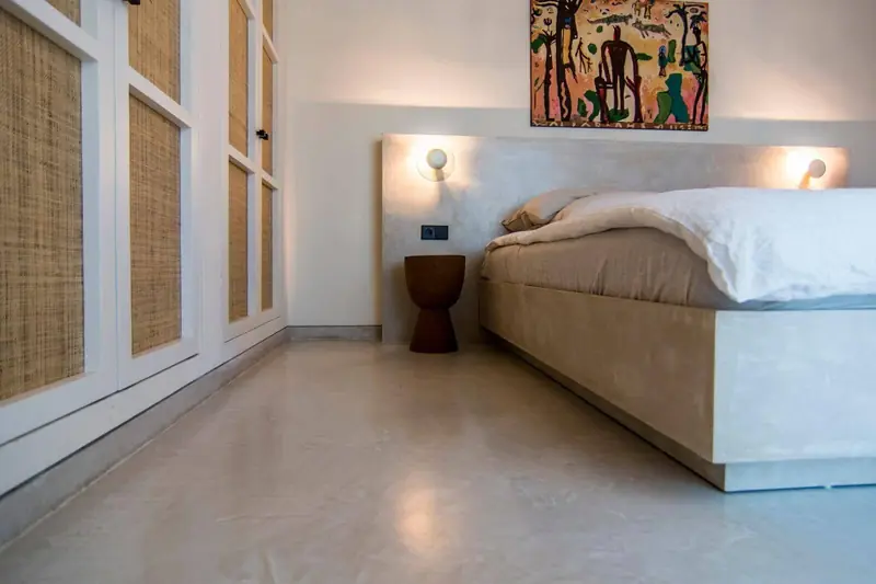 Dormitorio con suelo de microcemento y cama de obra revestida