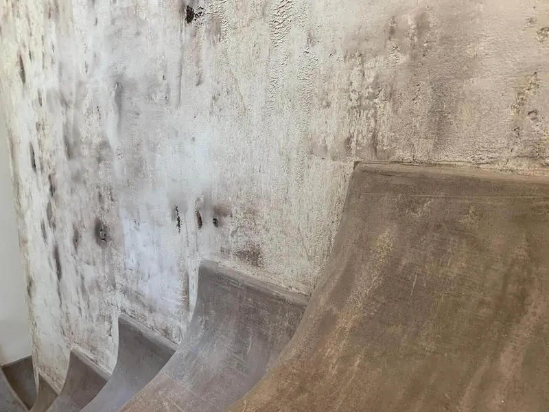 Escalera curva de microcemento junto a una pared con acabado envejecido