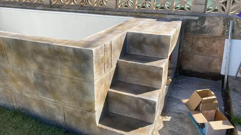Escalera de acceso a la piscina elevada, revestida en piedra artificial