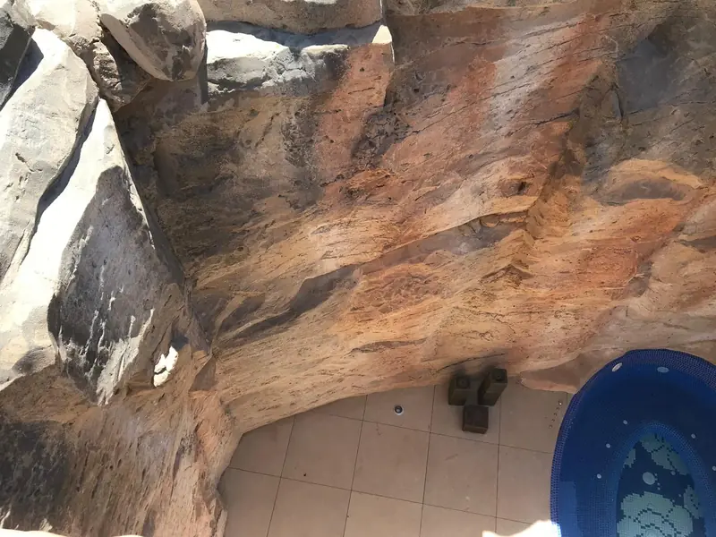 Gruta de roca artificial con jacuzzi integrado junto a la piscina