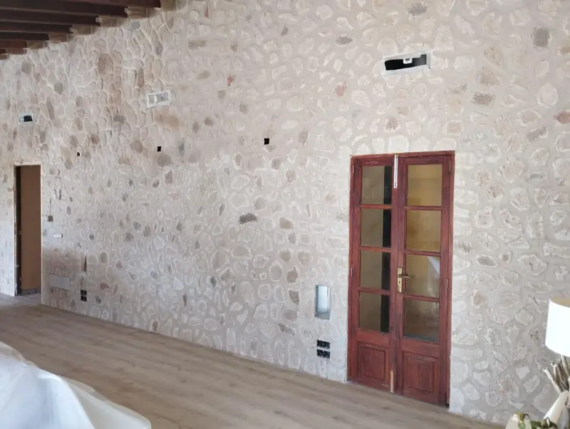Pared interior con acabado de piedra vista y puerta de madera
