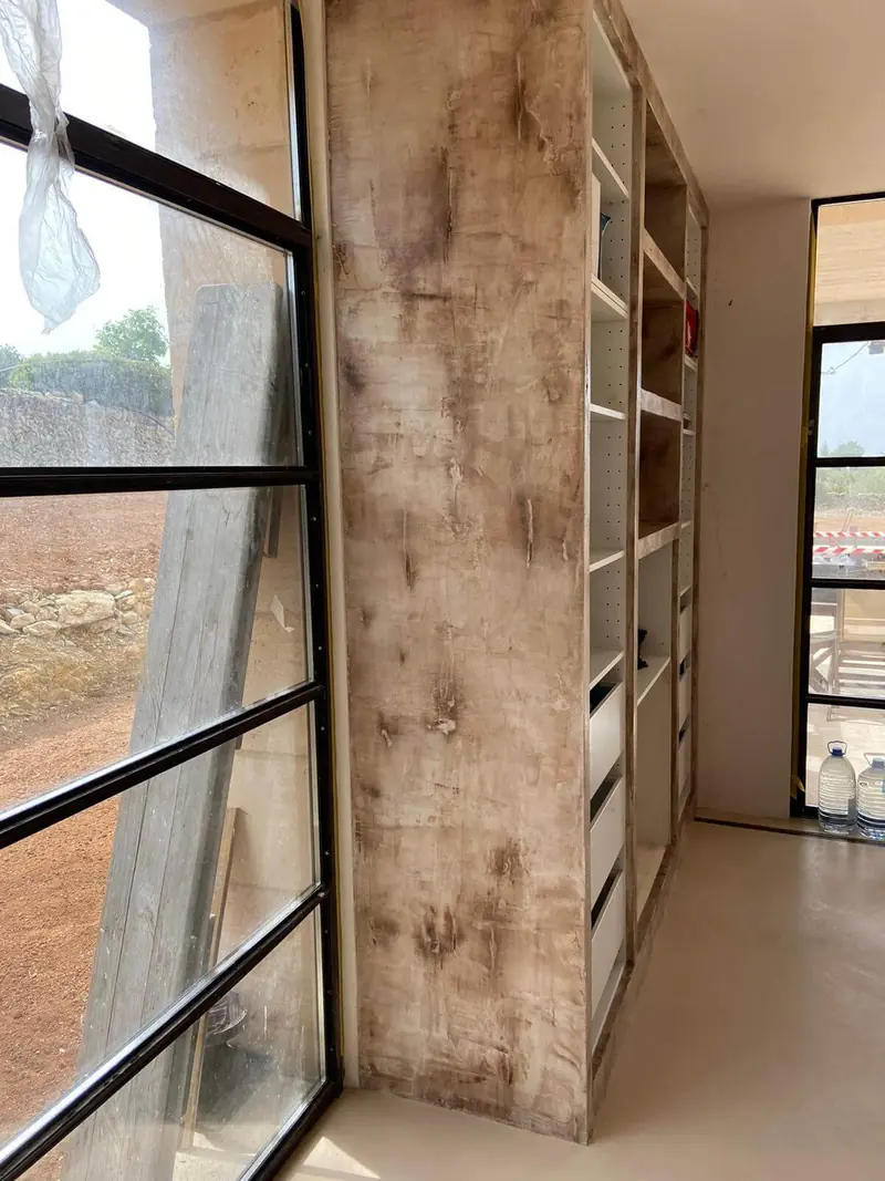 Pared de microcemento envejecido junto a un ventanal de hierro
