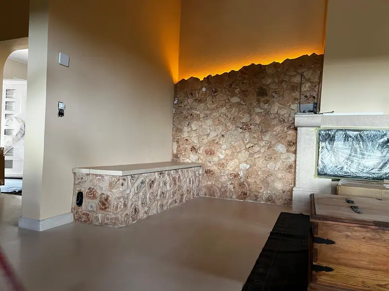Pared de piedra tematizada con iluminación indirecta y banco de obra