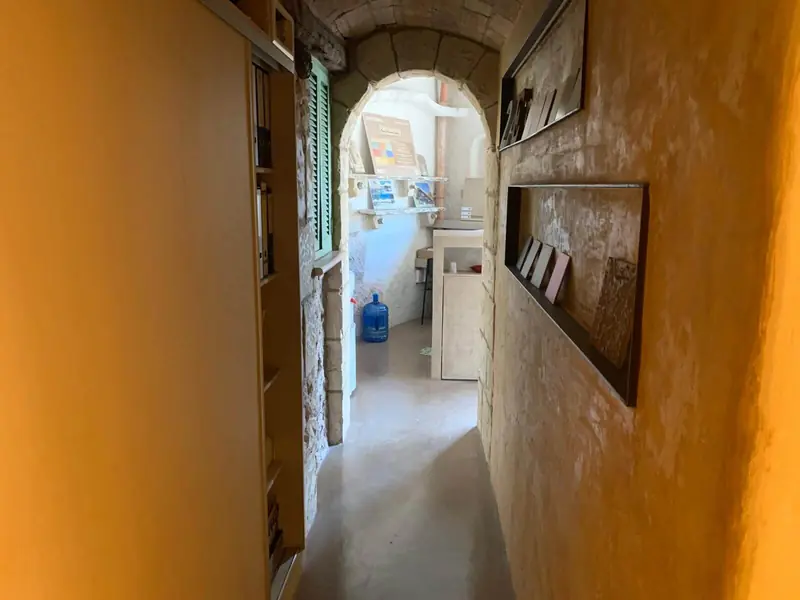 Pasillo con suelo continuo de microcemento hacia un arco de piedra