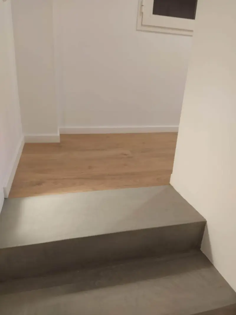 Peldaño de microcemento gris como transición hacia un suelo de madera