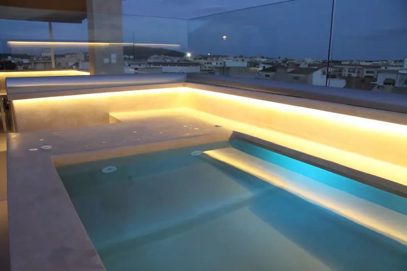 Piscina de ático iluminada al anochecer con vistas a la ciudad