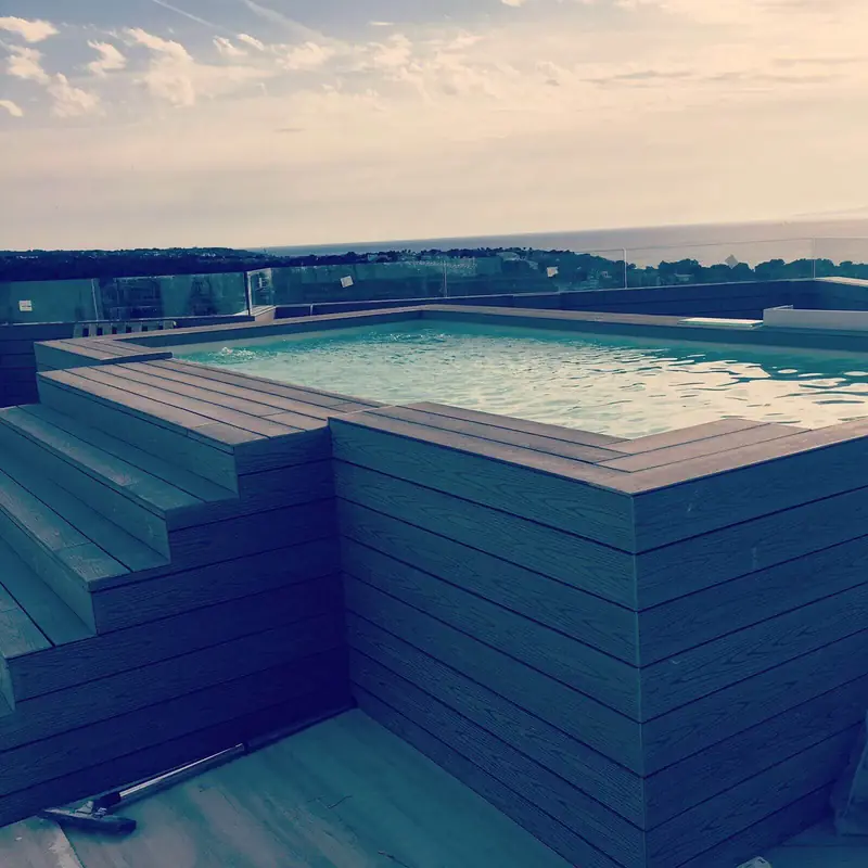 Piscina en un ático revestida en madera, con vistas al mar