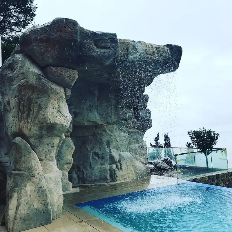 Piscina desbordante con cascada desde una roca artificial