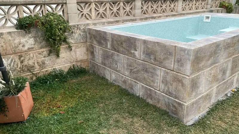 Lateral de la piscina elevada con acabado de bloques de piedra