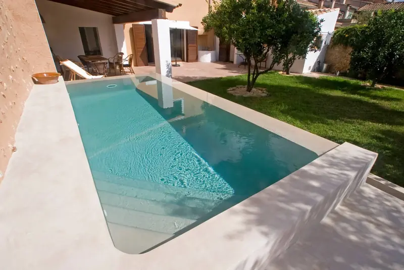 Piscina con vaso, borde y playa de microcemento en un jardín