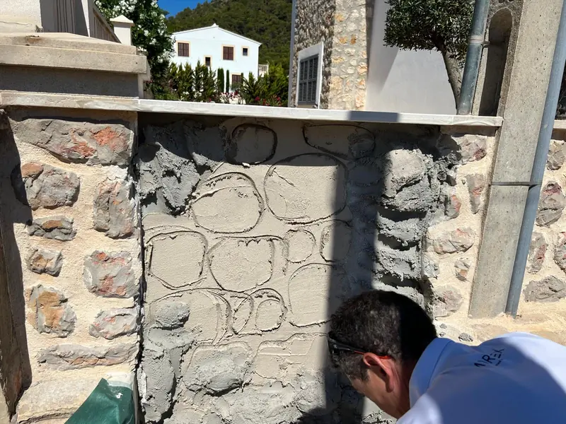 Artesano tallando a mano las juntas de un muro de piedra