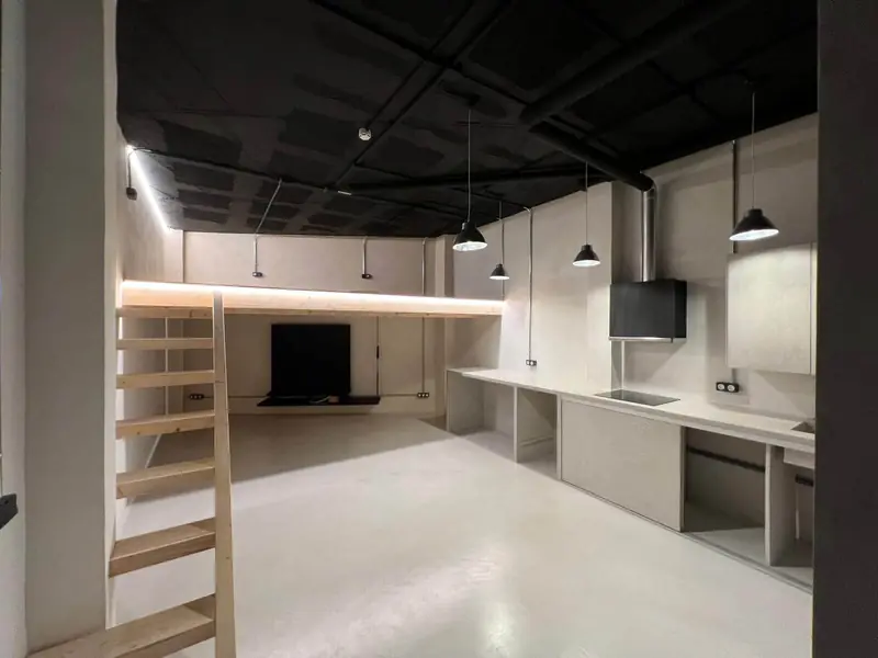 Después: loft con suelo y paredes de microcemento, cocina lineal y altillo de madera