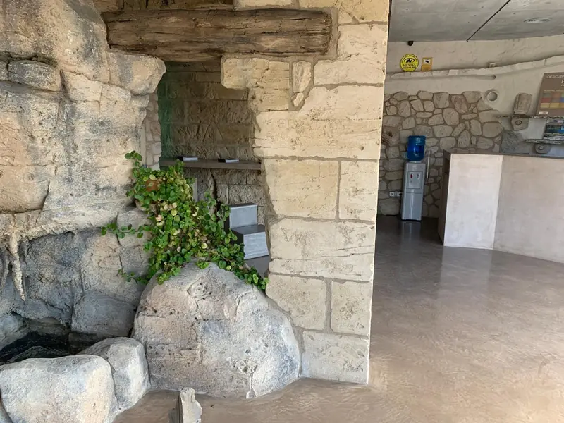 Rincón con roca artificial, viga de madera envejecida y plantas