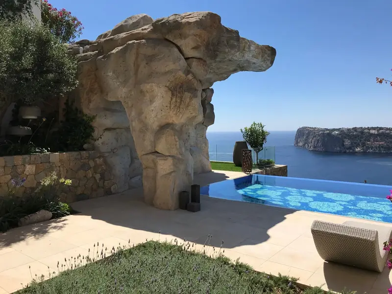 Arco de roca artificial junto a una piscina con vistas al mar