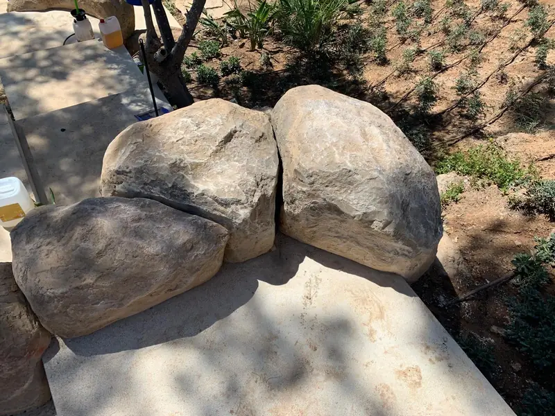 Rocas decorativas artificiales en un jardín con vegetación